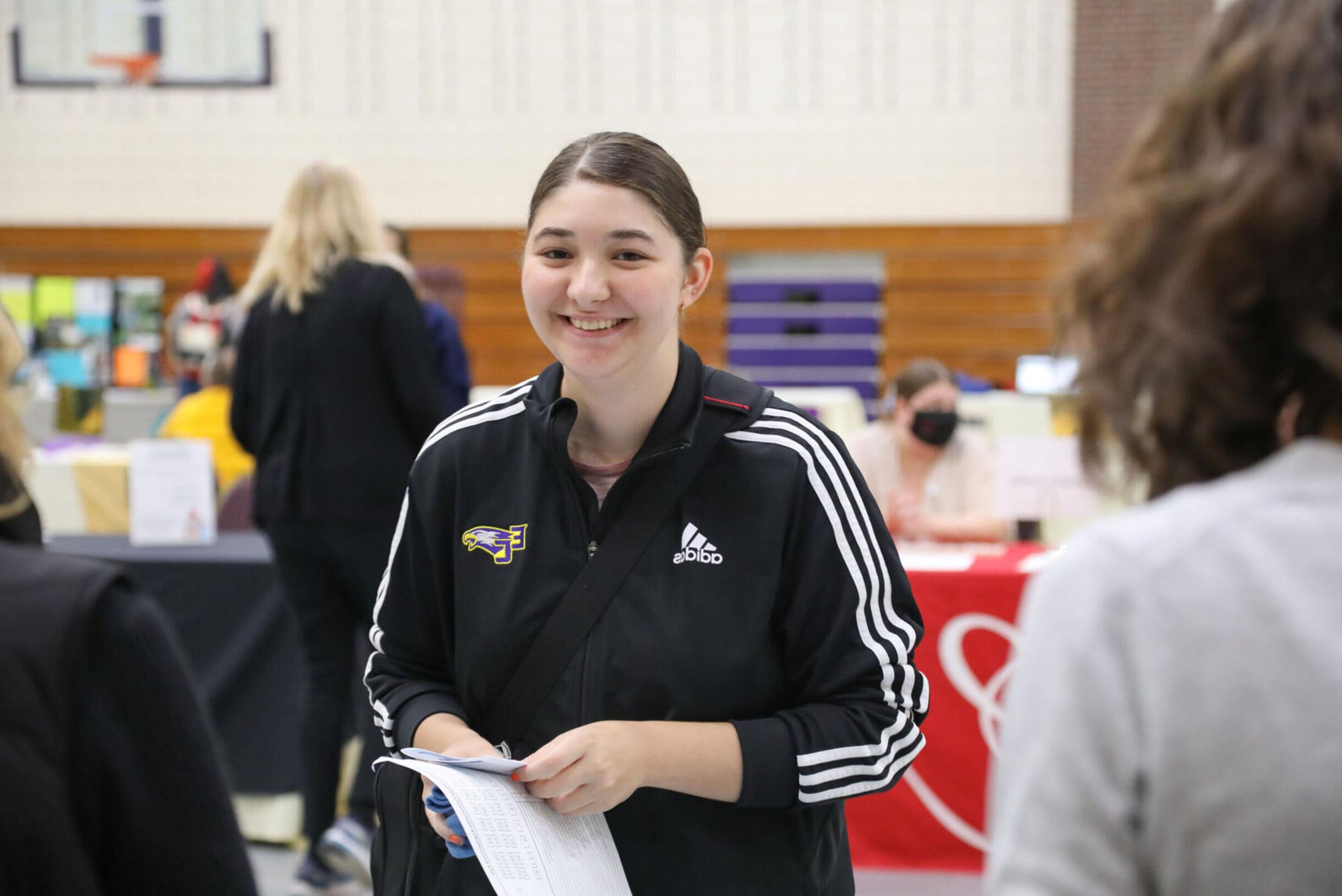 A female student smiles while visiting a booth at the Community Engagement Fair